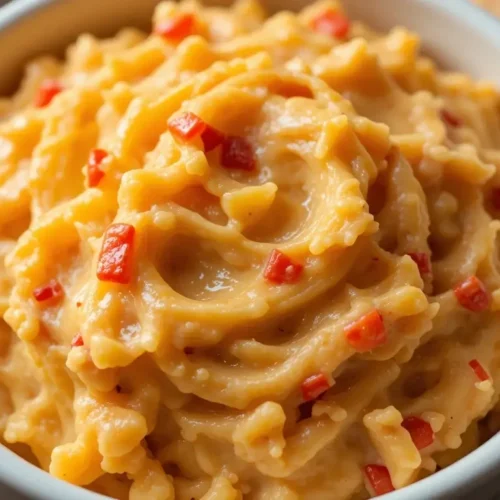 A rich and creamy old fashioned pimento cheese recipe served in a white bowl, featuring a smooth, cheesy texture with diced pimentos, perfect for spreading or dipping.