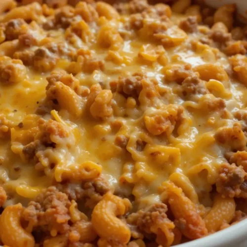 A freshly baked beefaroni recipe in a white casserole dish, featuring elbow macaroni, seasoned ground beef, rich tomato sauce, and melted cheddar cheese.