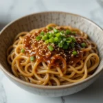 A delicious bowl of hibachi noodles topped with a rich, savory sauce, garnished with fresh green onions and sesame seeds. Perfect for a homemade hibachi noodles recipe.