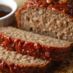 Delicious homemade meatloaf recipe Lipton onion soup, glazed with a tangy sauce, sliced and served on parchment paper with a side of rich dipping sauce.